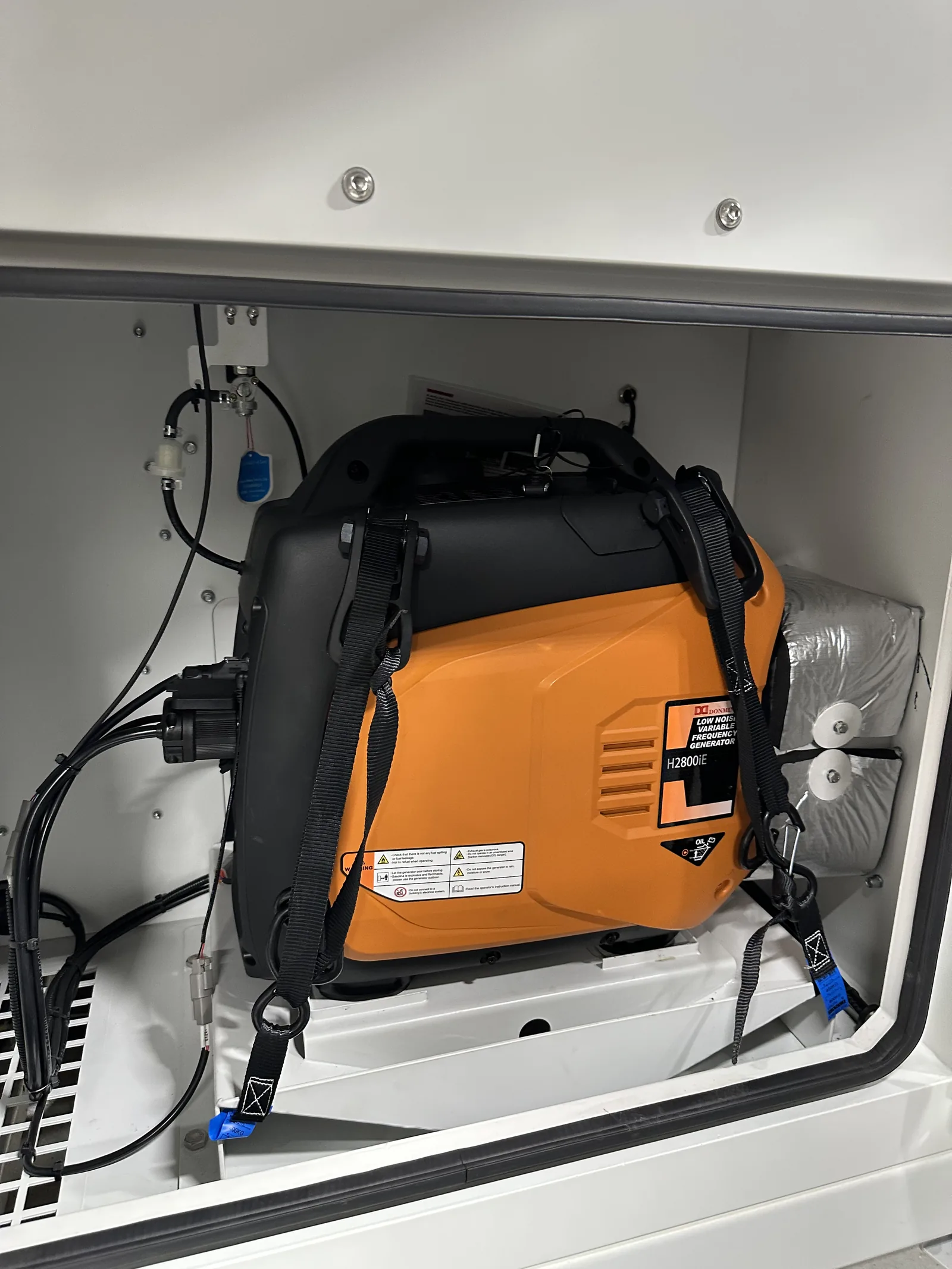 The onboard gasoline generator strapped down in its compartment on the trailer